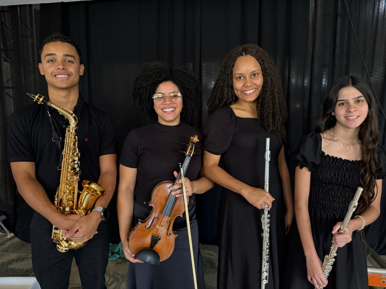 Quatro músicos da orquestra com saxofone, violino e flautas no encontro em Passos.